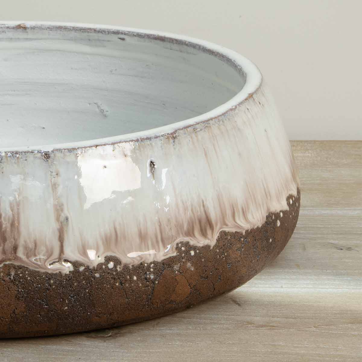 Low terracotta decorative bowl with aged cream glaze and rustic brown base - close up