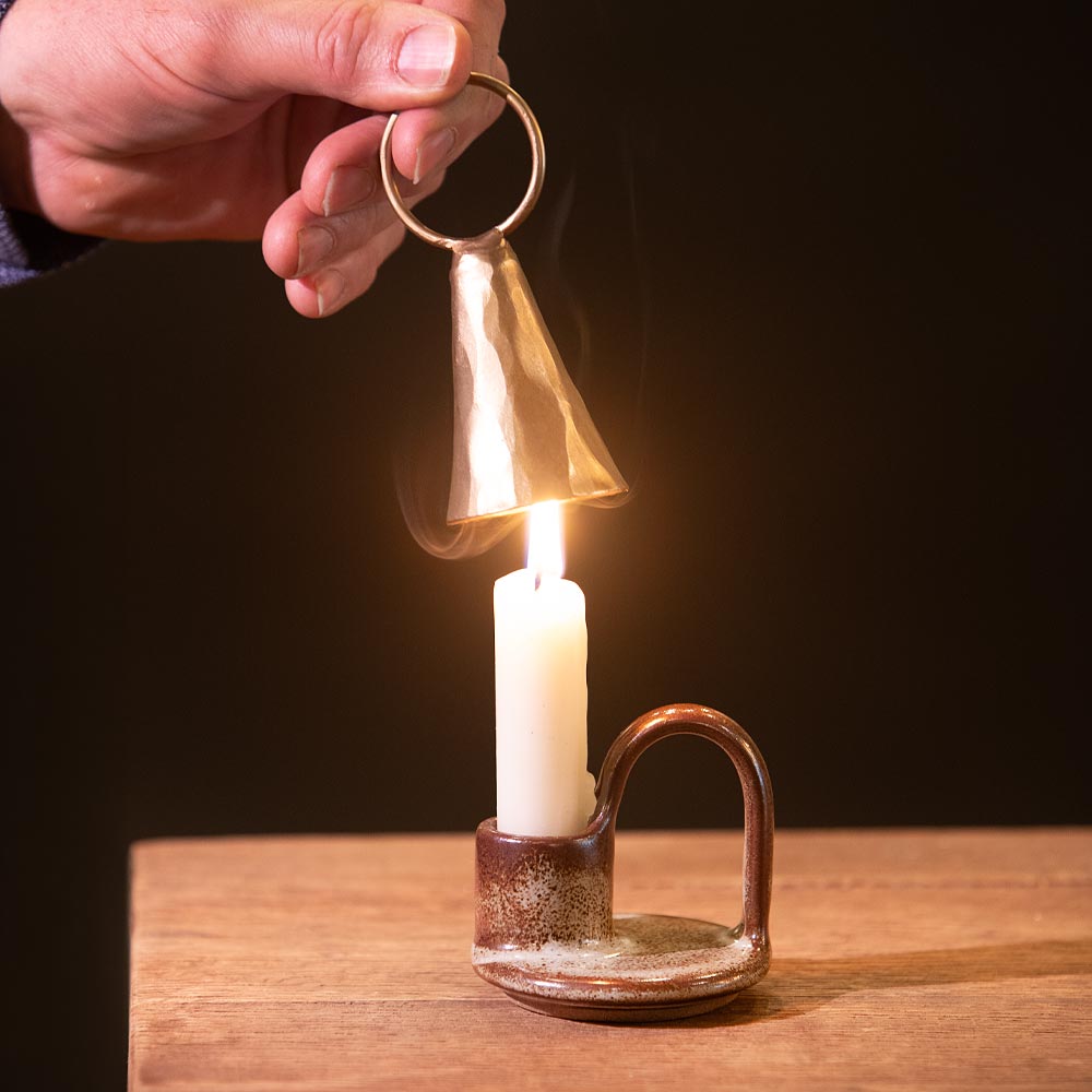 Using a candle snuffer. to extinguish a candle