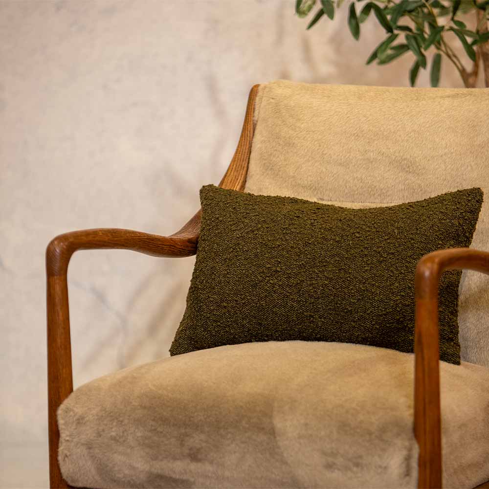 Green textured pillow on a beige armchair with a neutral background