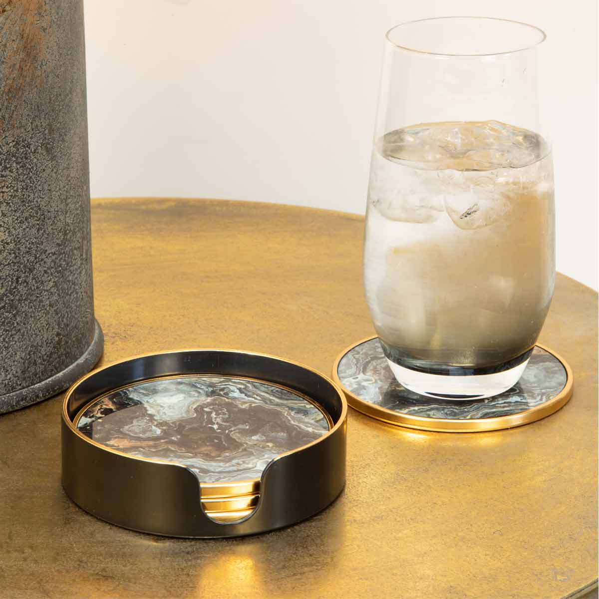 Glass of water on black marble effect coaster on gold table