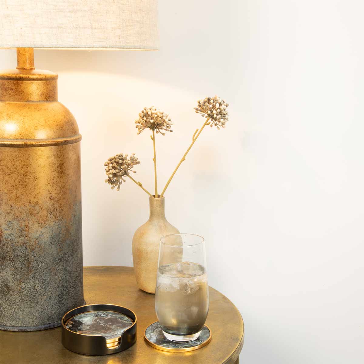 Black Marble Effect Coasters styled on gold side table with glass of water and ceramic vase