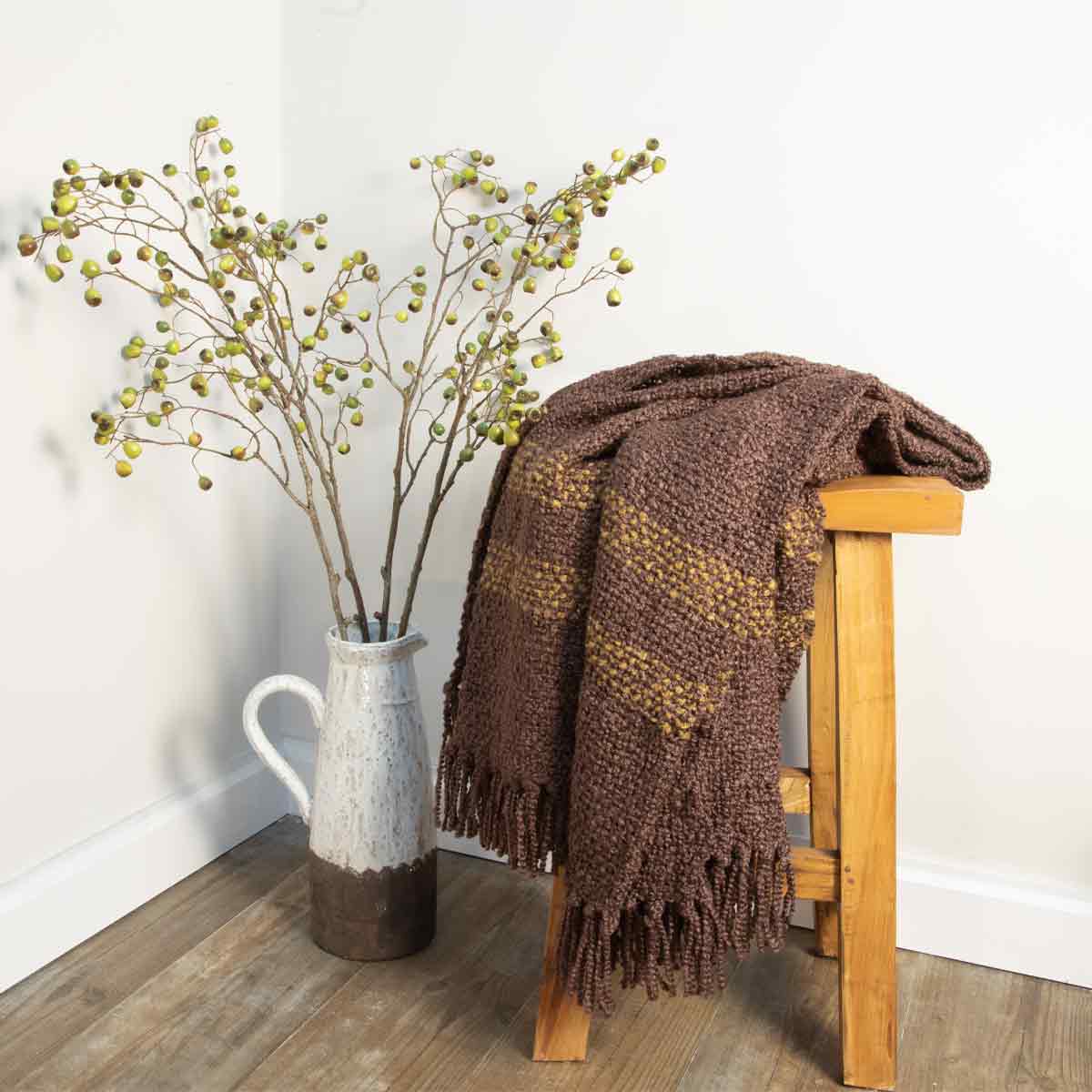 Braza Throw in dark brown with ochre accents, featuring soft woven fabric and fringed edges.