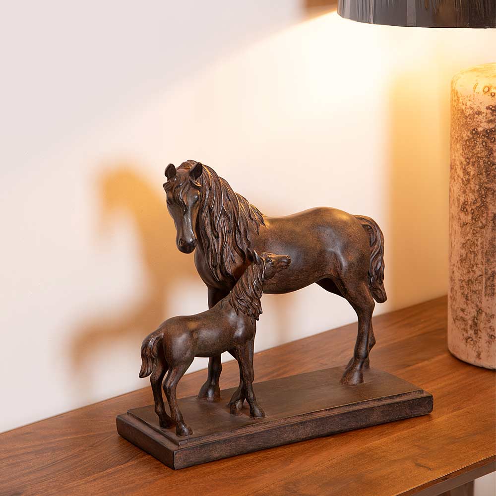 Bronze-effect sculpture of a mare and foal styled on a console with lamp