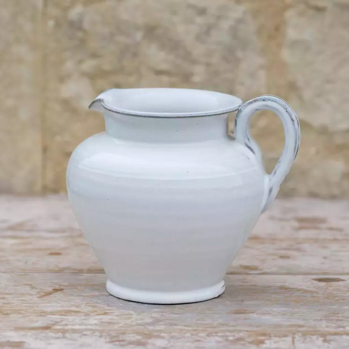 Carla White Glazed Jug – hand-crafted ceramic jug with food-safe white glaze styled on a weathered wooden table against a stone wall