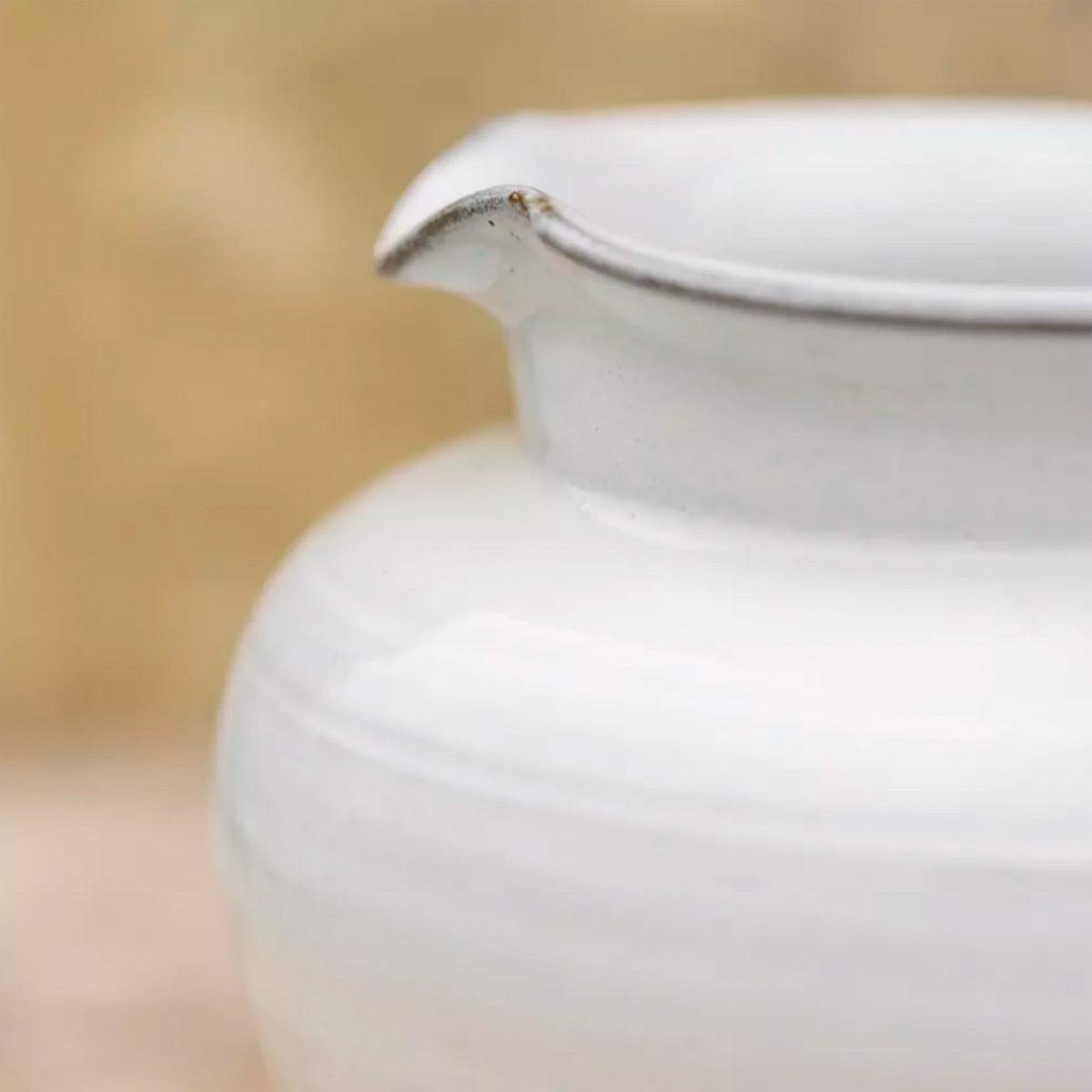 Carla White Glazed Jug – close-up of the jug’s flared spout and smooth white glaze with subtle ribbing, set on a wooden plank