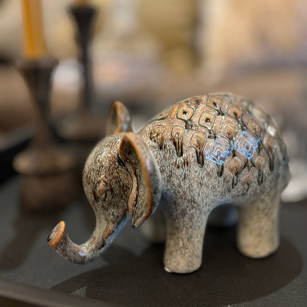 Decorative ceramic elephant figurine with intricate patterns on a reflective surface