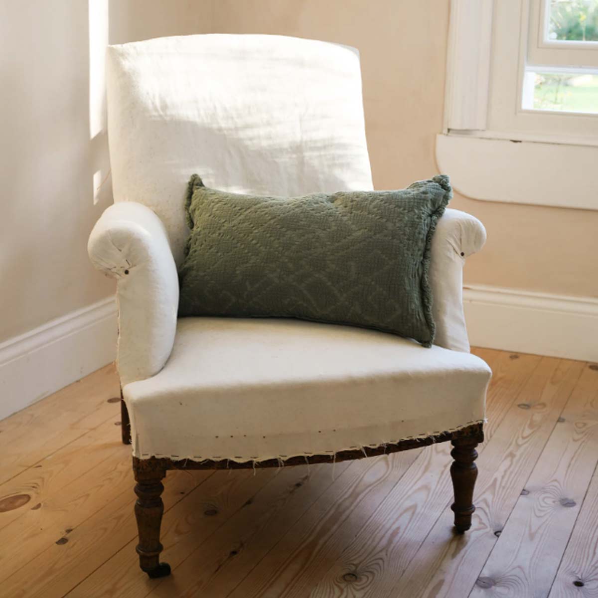 Chantilly Cushion in Olive – 100% cotton with lace-style waffle texture and frayed edges, styled on armchair in a rustic country interior