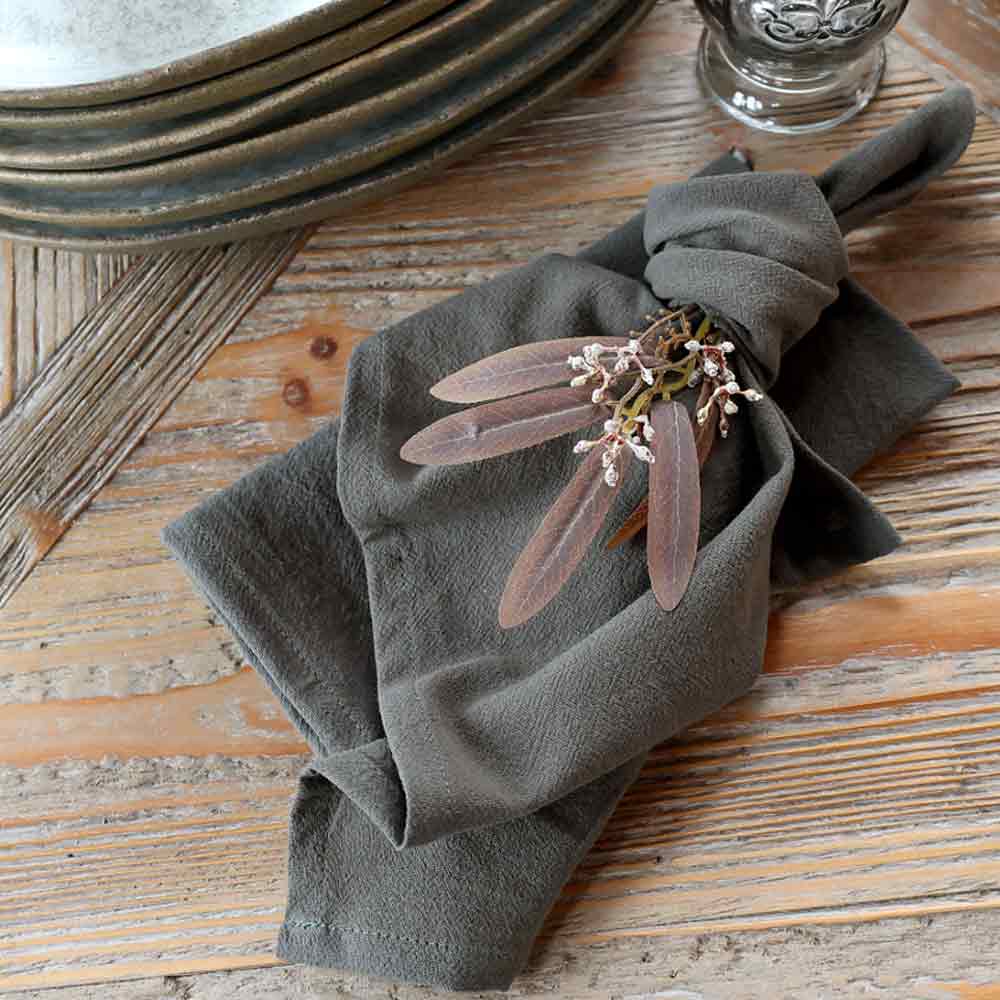 Dark olive green napkin with floral arrangement on a rustic table