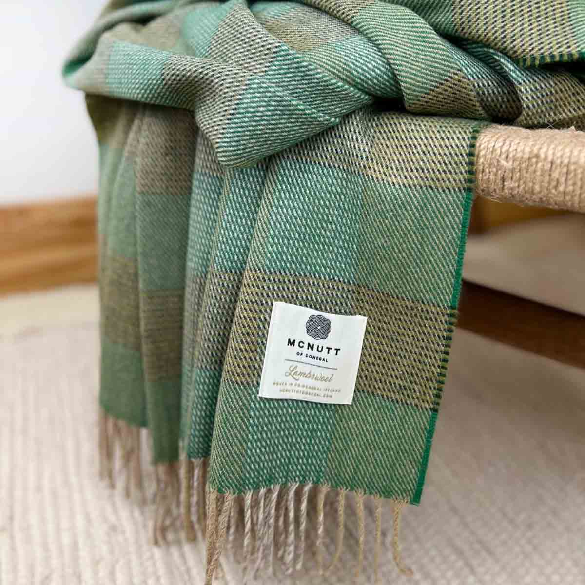 Enya Merino Lambswool Throw – McNutt of Donegal placeds on rustic chair