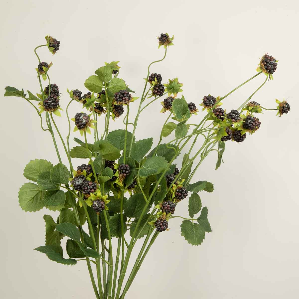 Bouquet of artificial blackberries with green leaves on a light background