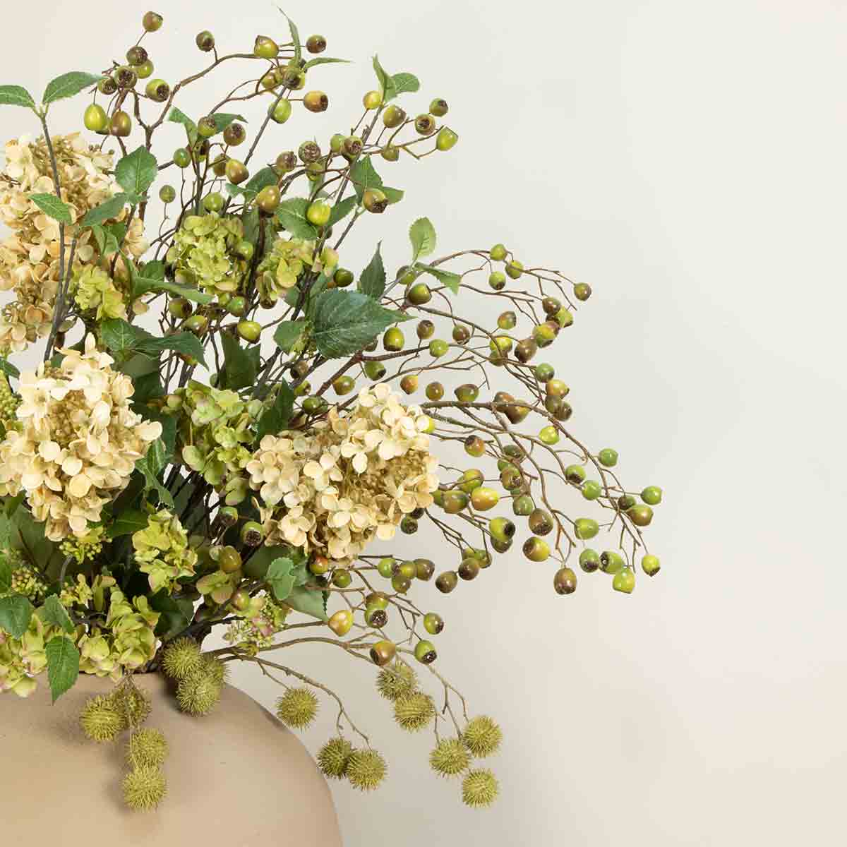 A display of artificial dual tone eucalyptus berry stems with hydrangeas and echinops in a ceramic vase.