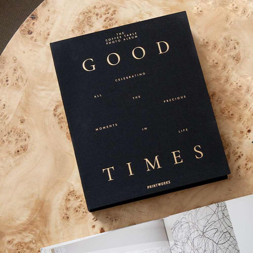 Black photo album titled 'Good Times' on a marble surface