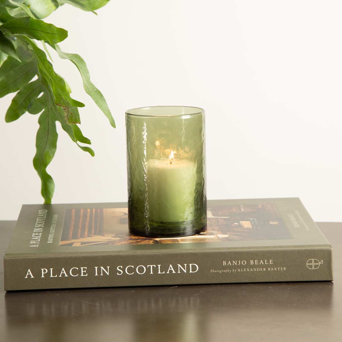 Green hammered glass tealight holder with candle on top of A Place in Scotland book