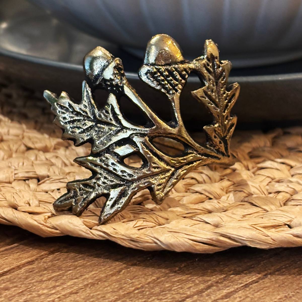 Joa Antique Gold Leaf Napkin Ring with intricate oak leaf and acorn design on a woven placemat