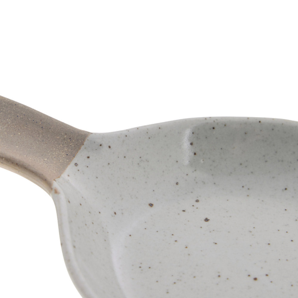 Brown-grey Joselia speckled stoneware spoon rest with curved shape and a beige handle on a white background
