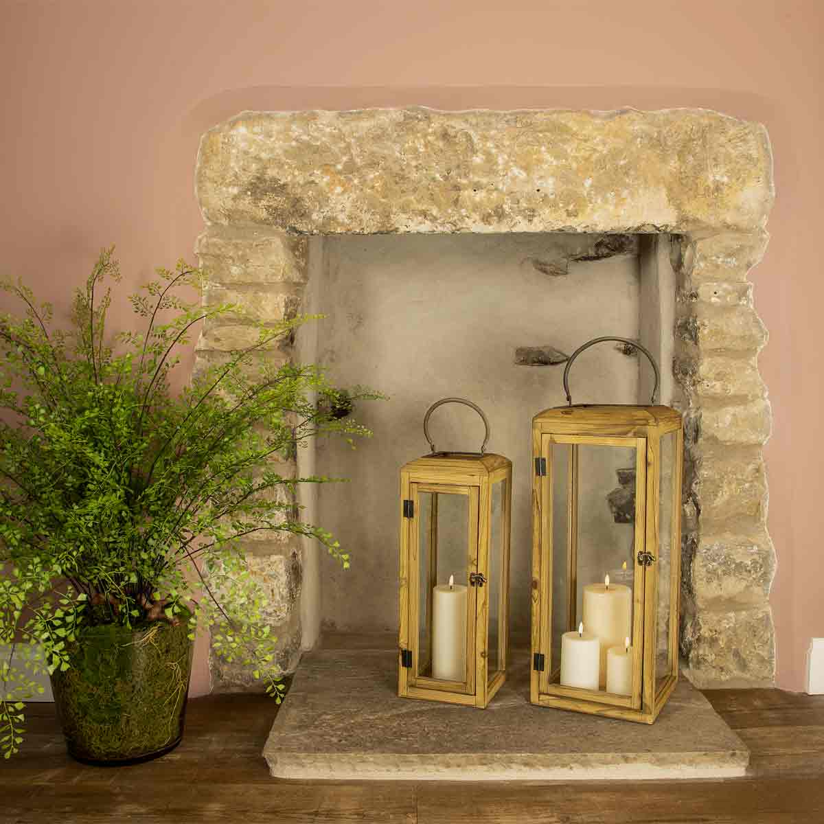 Lilly Wooden Lanterns – natural wood and glass lanterns styled in a stone fireplace with candles and greenery