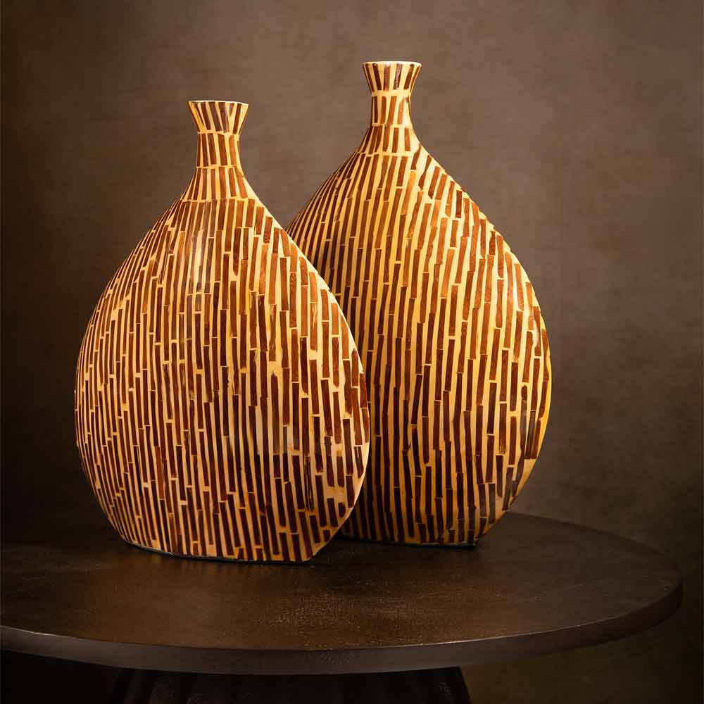 Two Lorca decorative vases with a vertical striped geometric pattern in warm natural wood tones, displayed on a dark round table against a dark brown background.