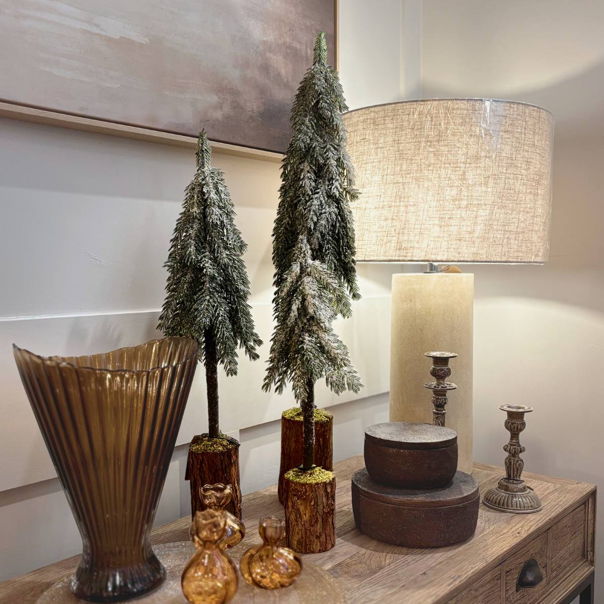 Mini Icy Pine Trees shown in three sizes alongside vases and lamp on a wooden surface.