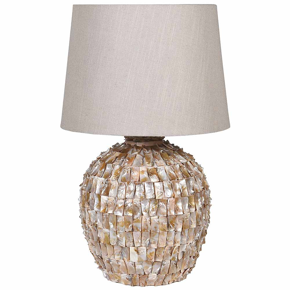 A table lamp with a textured, scalloped shell-covered base in beige and cream tones, topped with a light beige linen drum shade, shown against a plain white background.