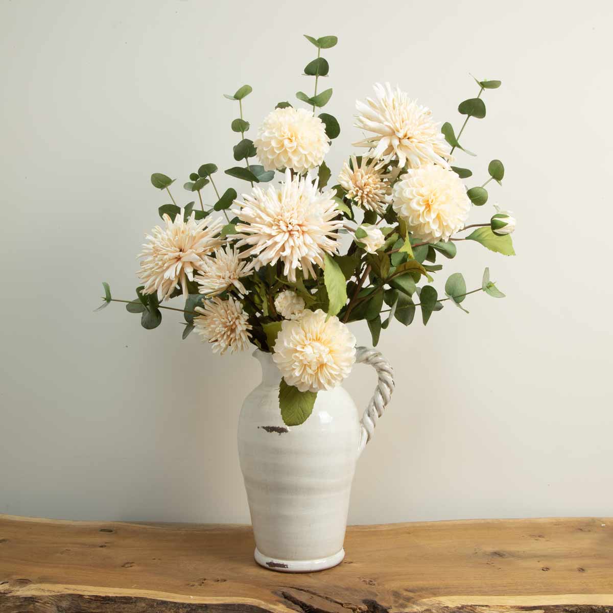 Off-white ceramic jug with twisted handle styled with faux flowers – 310mm tall