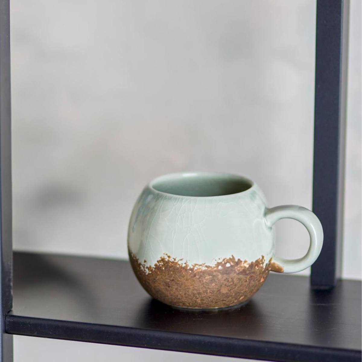 Paula stoneware mug with light blue and brown reactive glaze displayed on a shelf