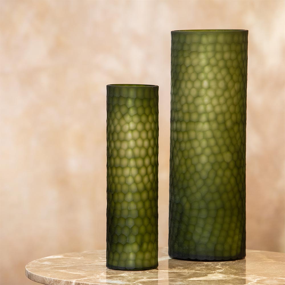 Two green textured vases on a marble surface with a beige background