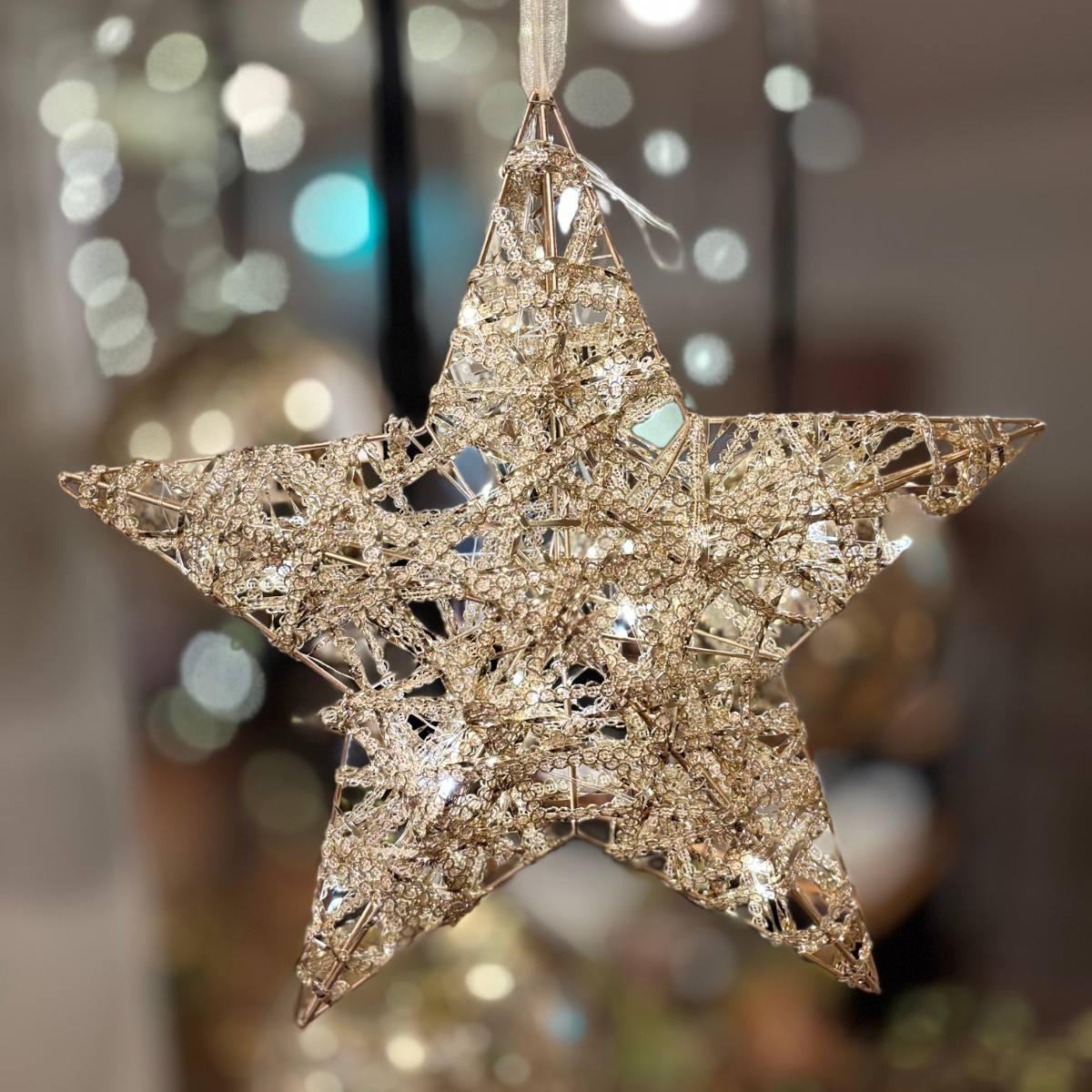 Decorative Raif Gold LED Sparkling Star ornament with a glittery finish against a blurred festive background
