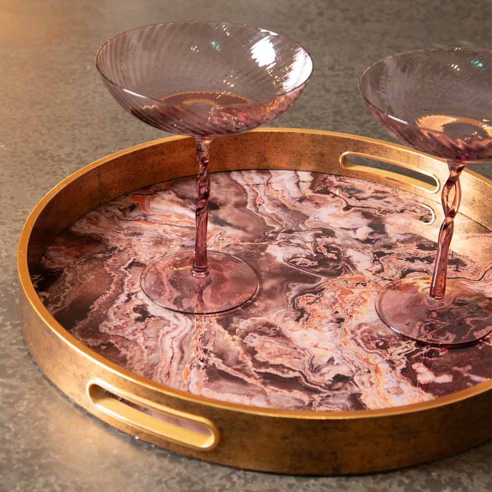 Round Marble-Effet tray in antique rose with gold rim and handles, featuring two pink glass champagne coupes.