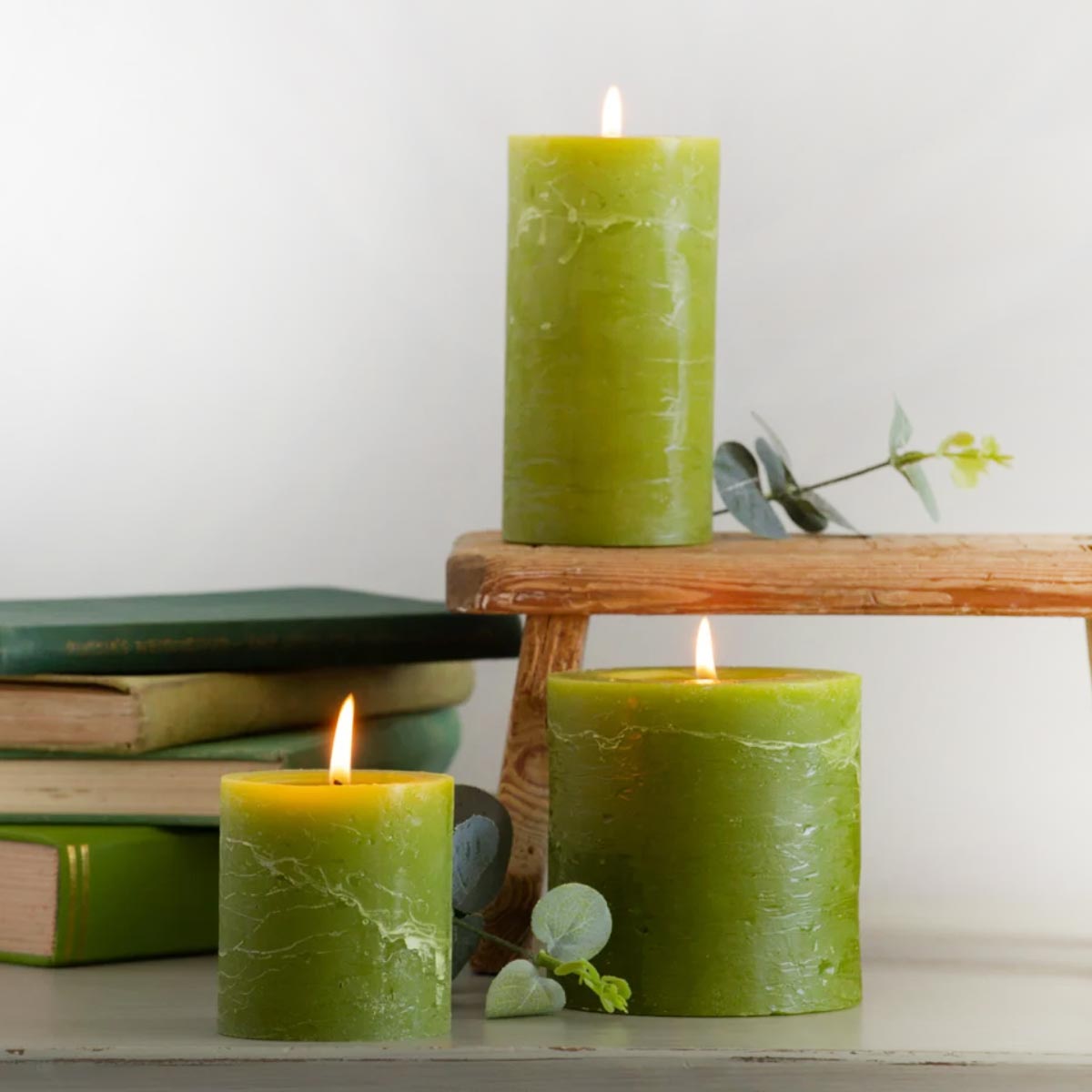 Fern Green Rustic Pillar Candles in small, medium, and large sizes with vintage books and greenery