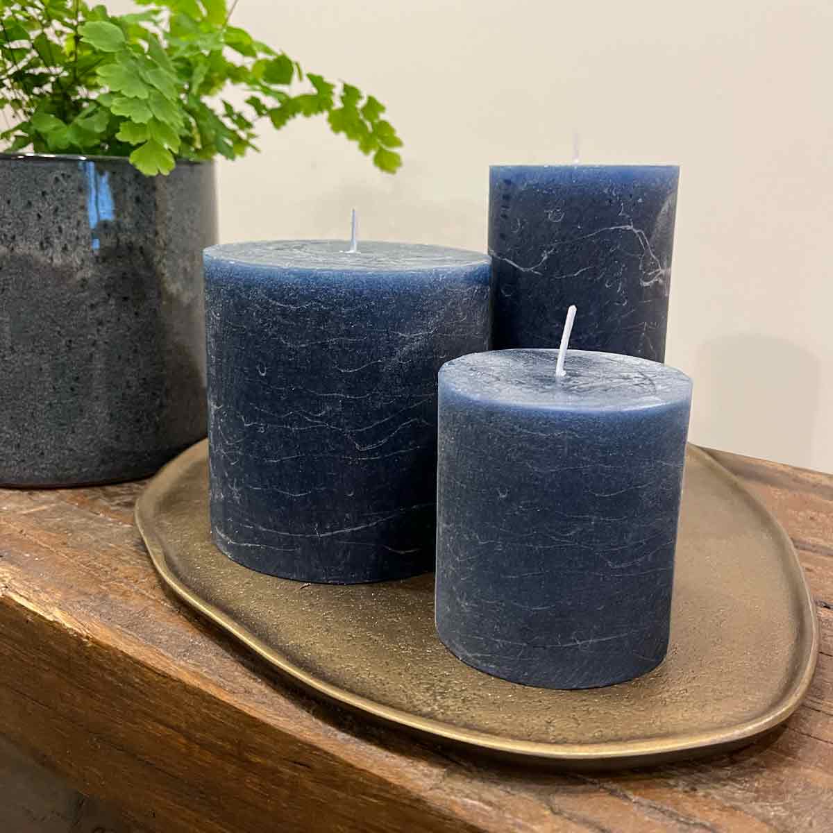 Inky Blue Rustic Pillar Candles in small, medium, and large sizes on a brass tray with a green plant