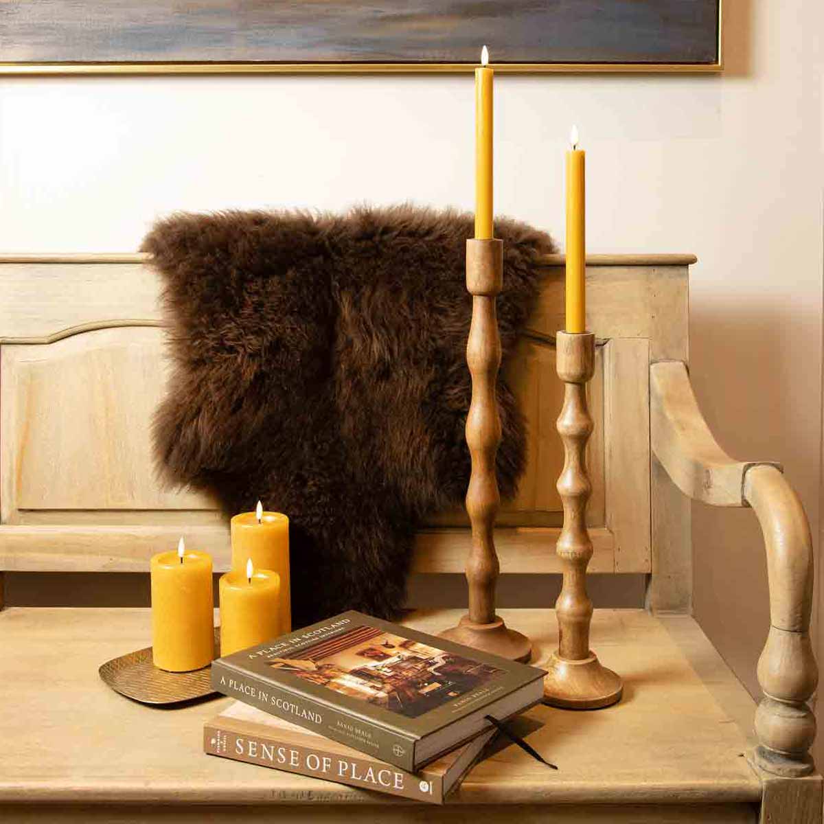 Set of two saffron LED dinner candles made from real wax with flame-effect glow in wooden candlestick holders displayed on rustic bench