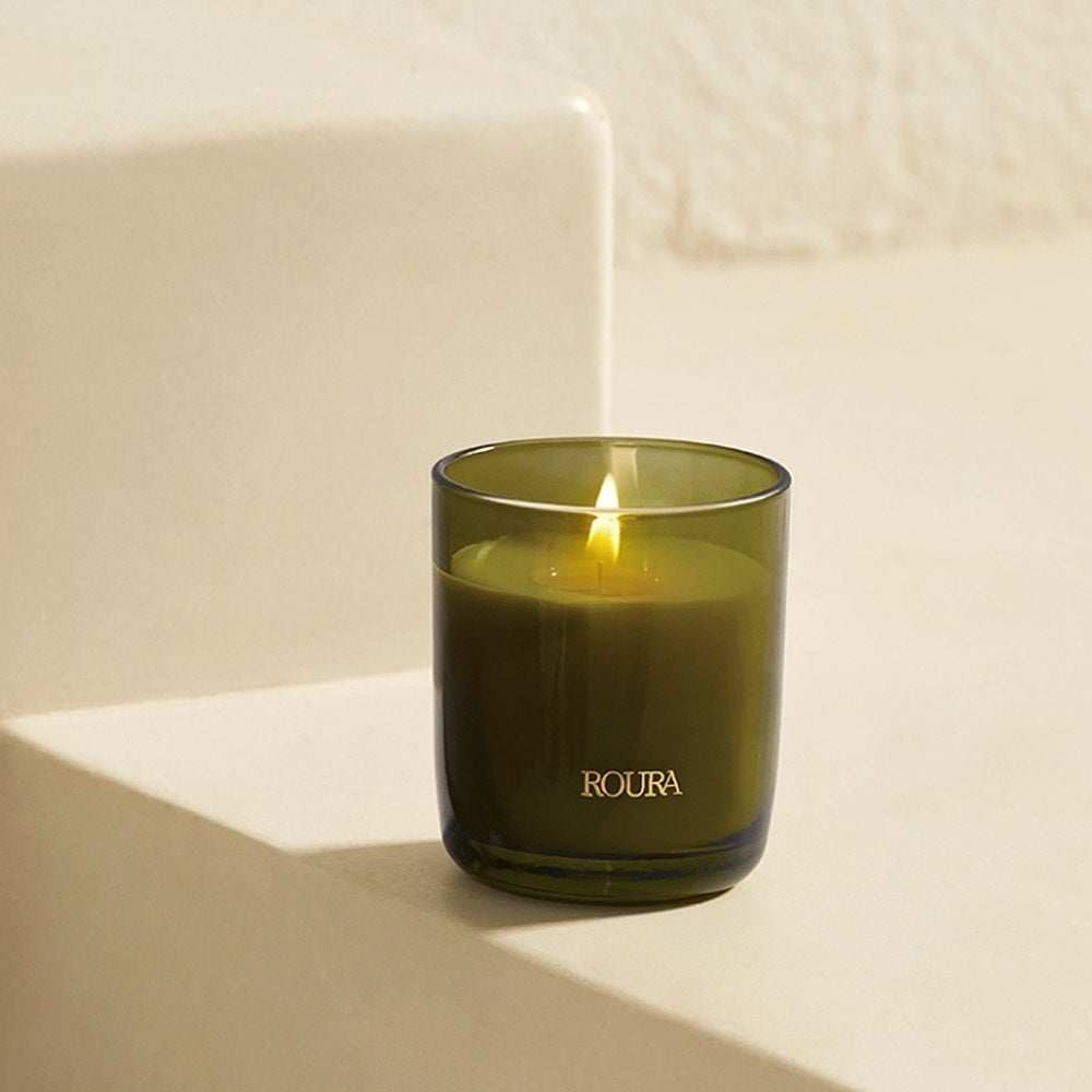 Secret Garden Roura candle in green glass jar with soft floral fragrance on a beige background