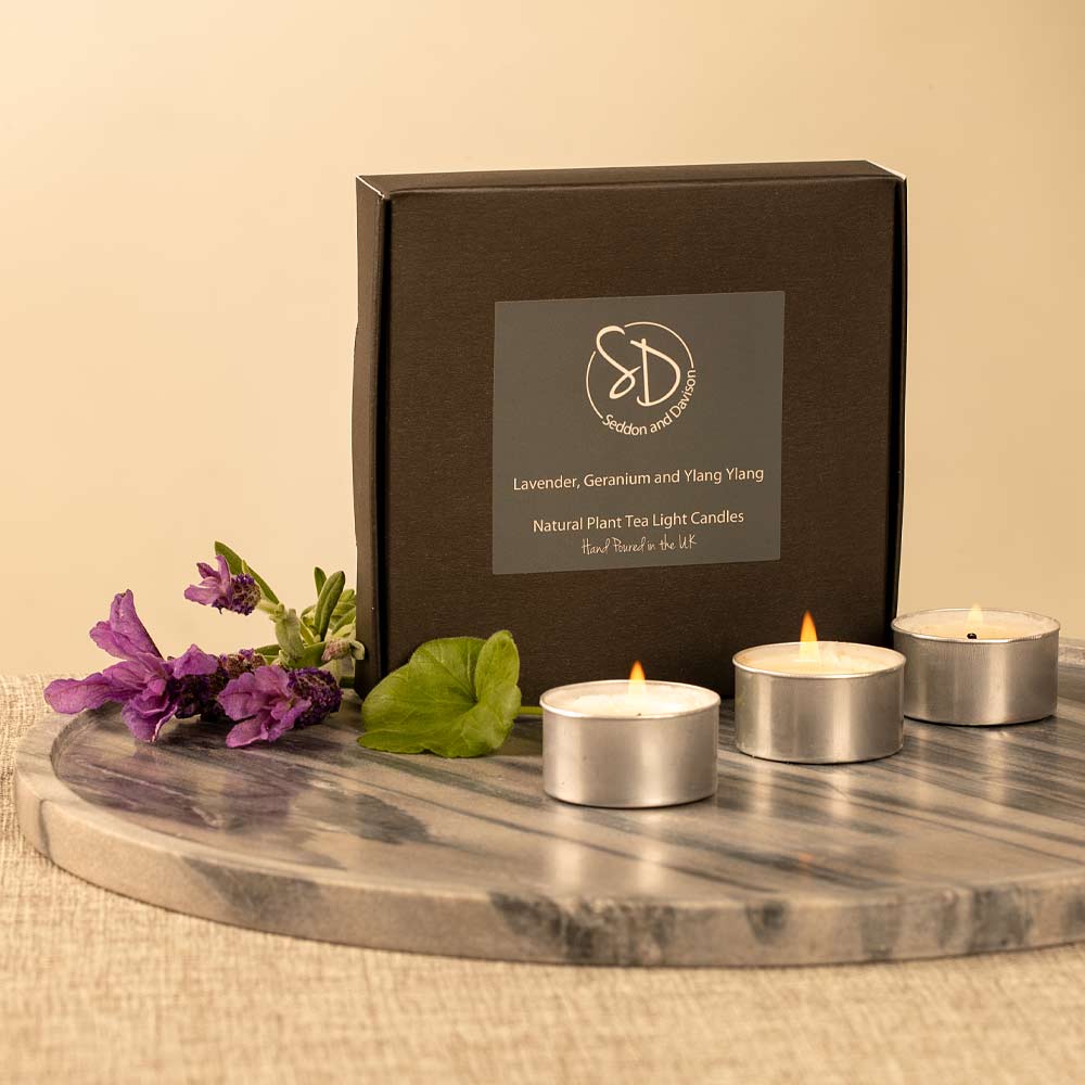 Set of 9 Lavender, Geranium and Ylang Ylang tea light candles with a decorative box on a marble surface