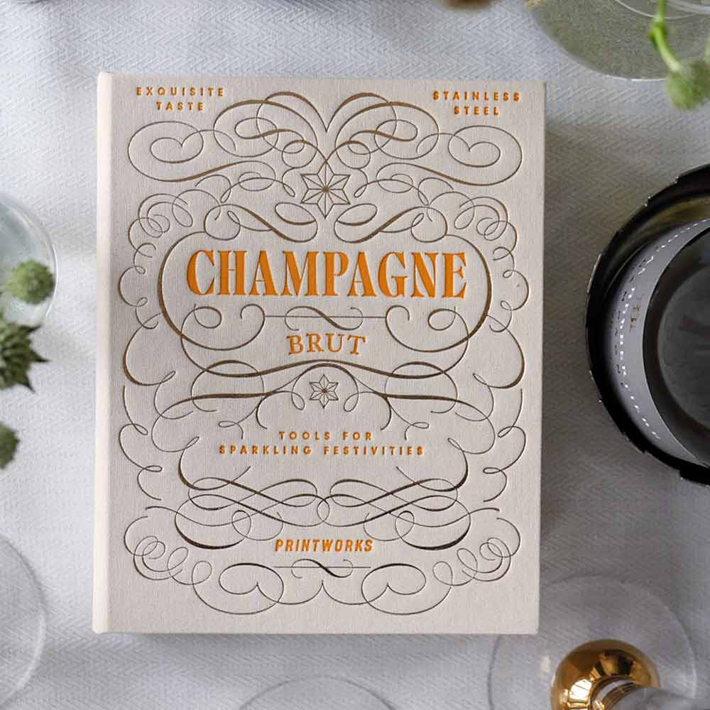 The Essentials - Champagne Tools Gift Set packaging with intricate design on a table