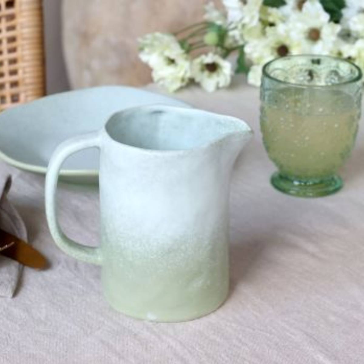 Light green Valence Porcelain Jug - pitcher and glass on a textured surface with flowers in the background