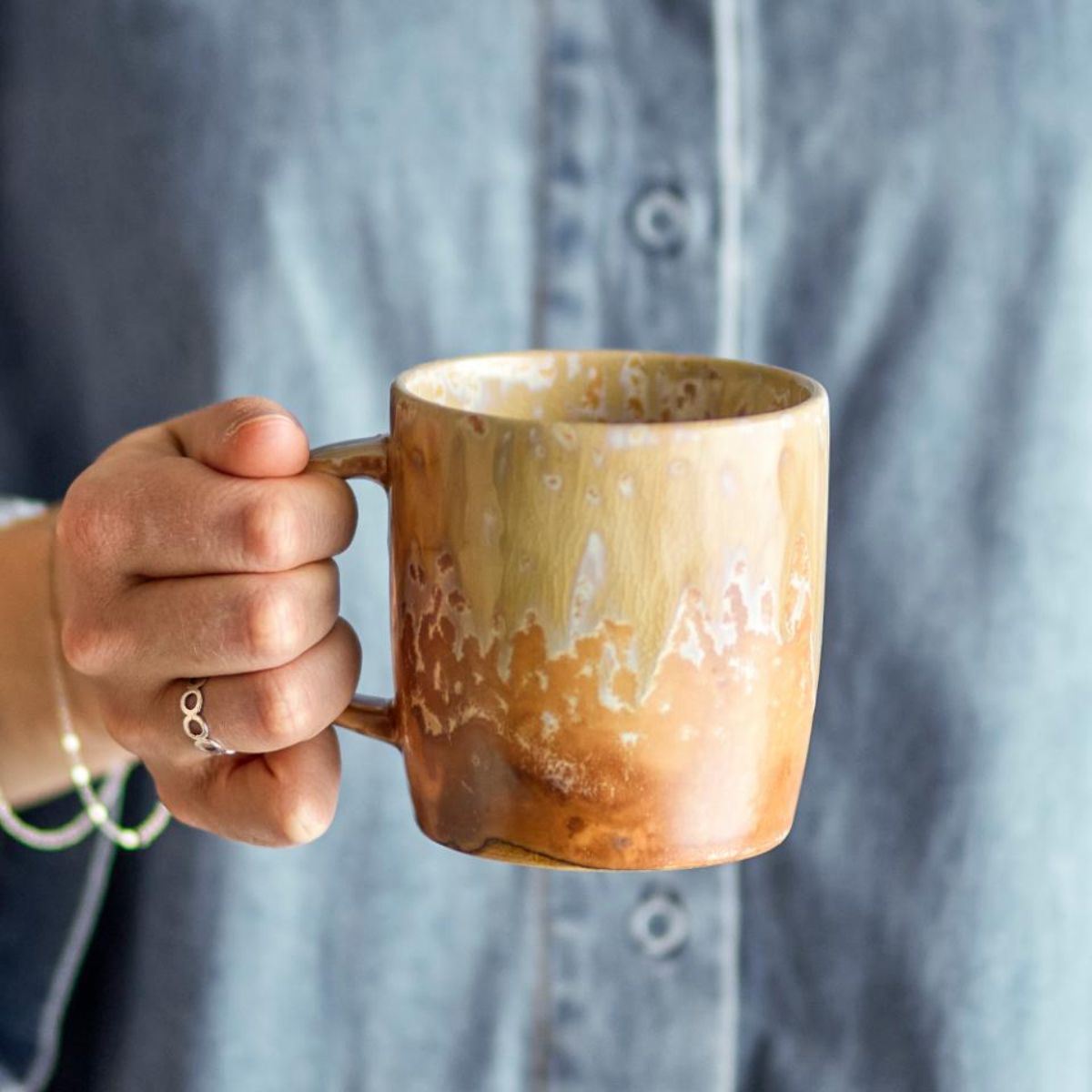 Hand holding a Milani stoneware mug with natural reactive glaze
