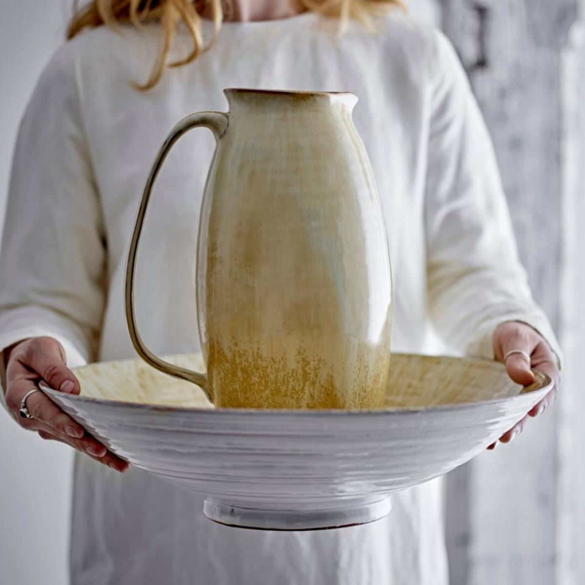 Saskia jug held in hands, showing size and golden glaze finish
