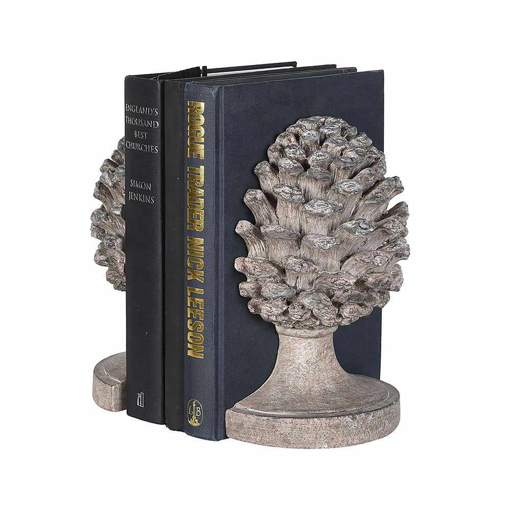 A pair of weathered looking  acorn bookends holding up two dark coloured books on a plain white background.
