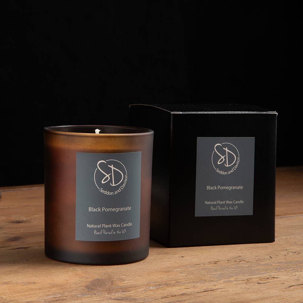 Black Pomegranate 30cl Scented Candle on a rustic wood table with a dark wall behind