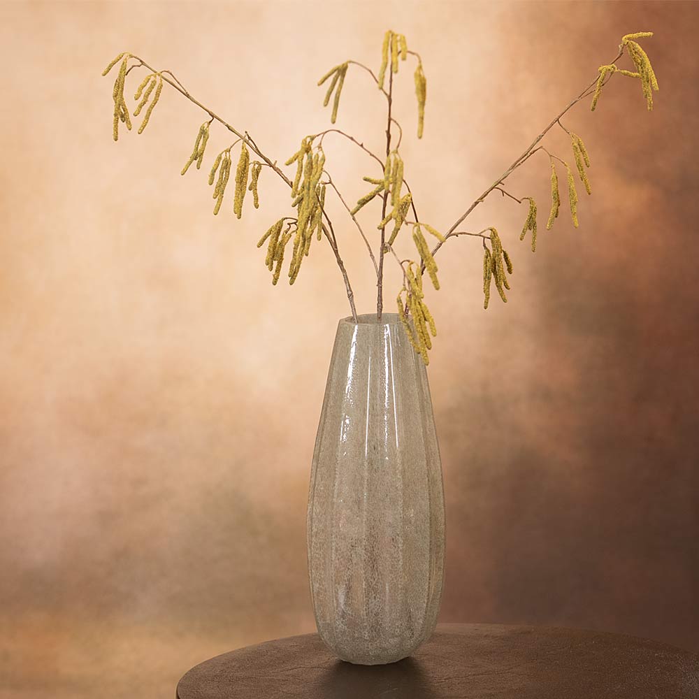 Decorative vase with branches and buds against a warm-toned background