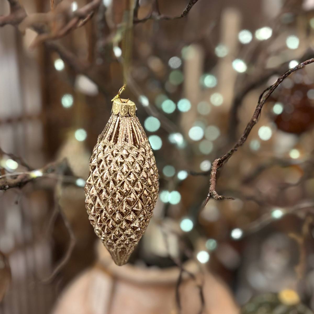 Bronze Diamond Finial Bauble changing on a branch with a blurred festive background