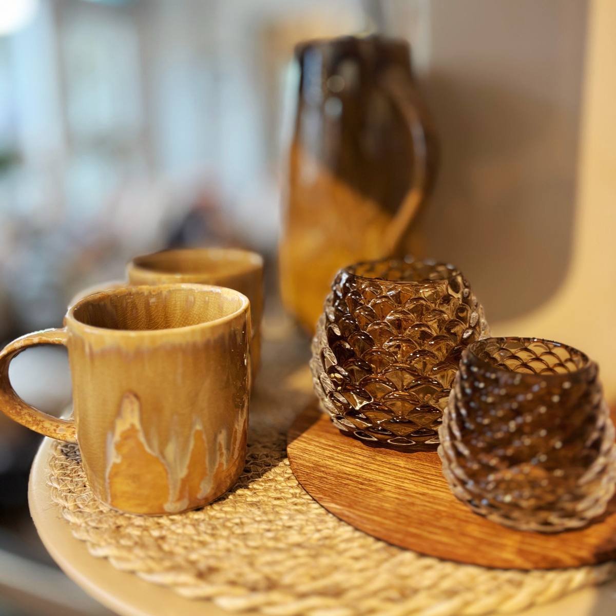 Large and Small Conia Candleholders styled with ceramic mugs on a woven surface