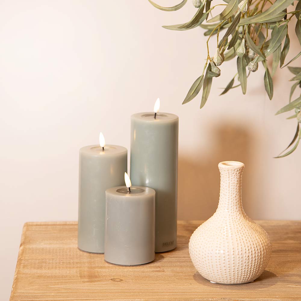 Three sand LED candles and a Cream Urchin Ceramic Vase on a wooden surface with a light background