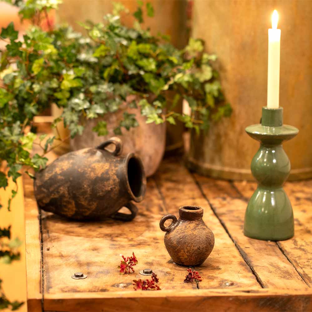 Decorative setting with Daiane Small Brown Terracotta Vase with Single Handle styled with rustic pots, a candle, and plants on a wooden surface.