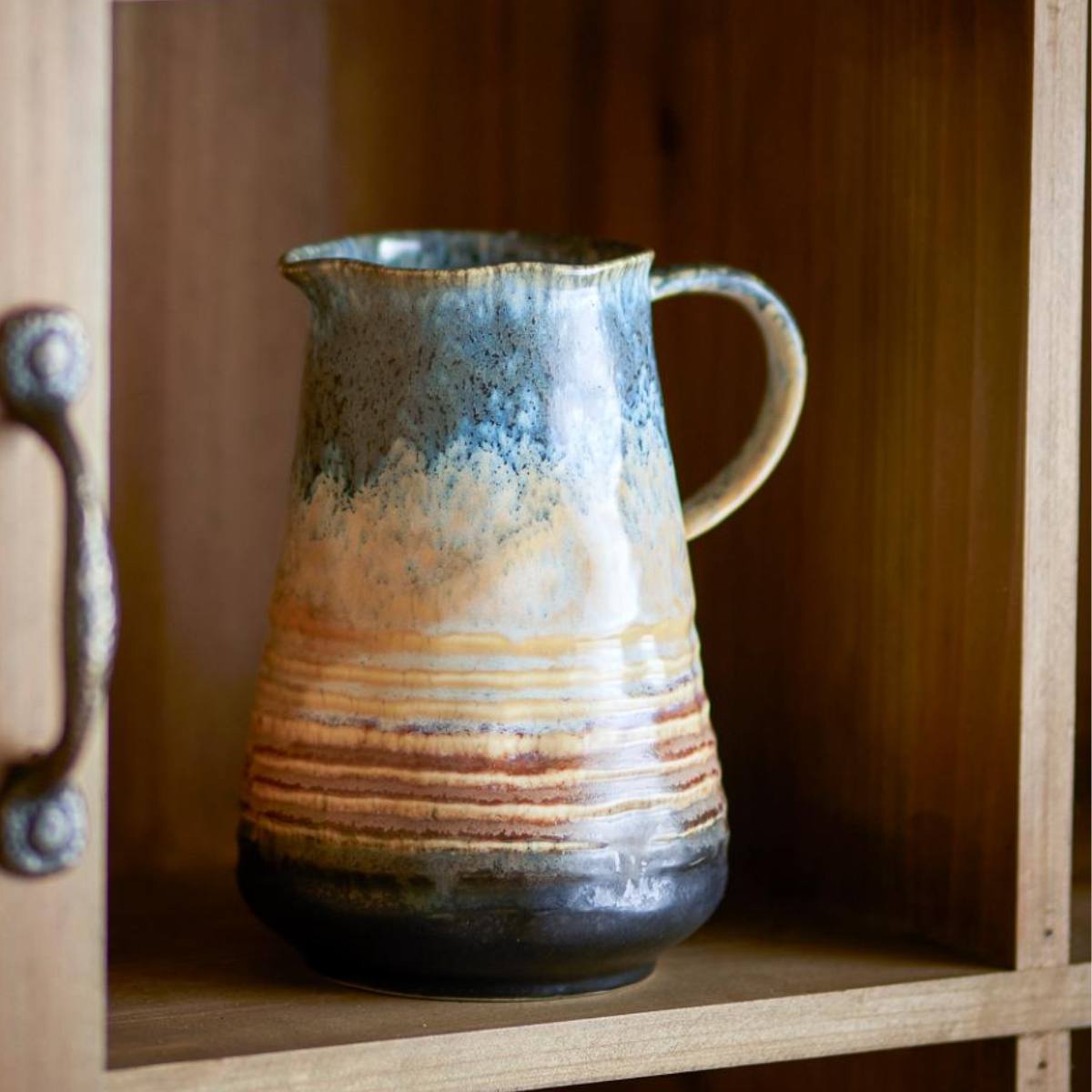 Ceramic Deana Jug with a brown and blue reactive glazed surface on a wooden shelf