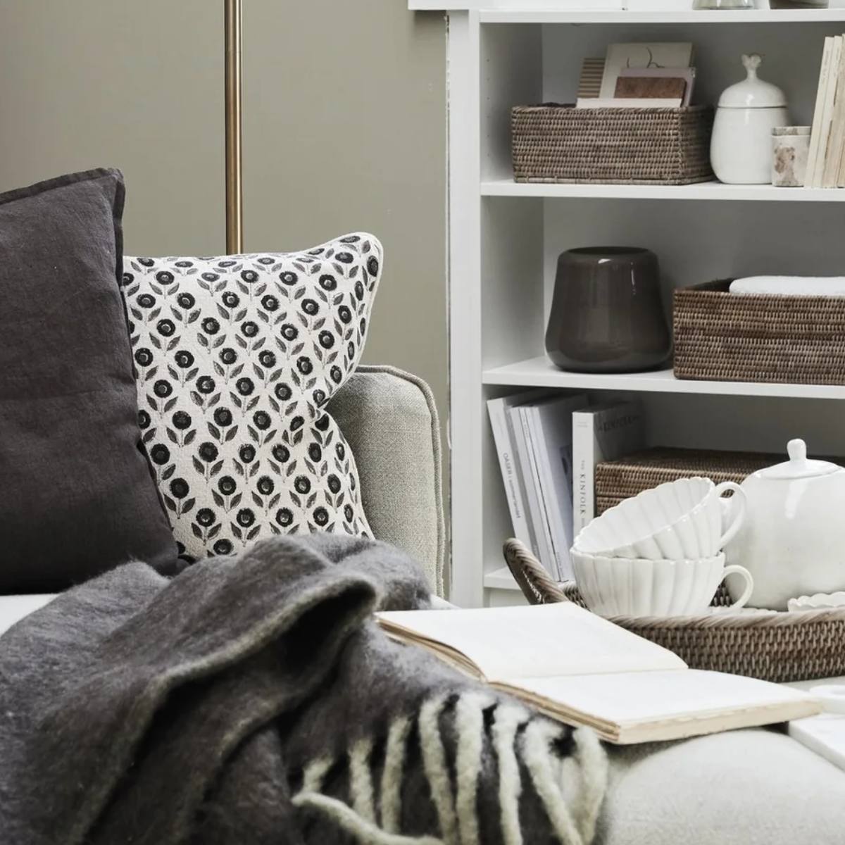 Cozy living room with a sofa, bookshelf, and decorative items including Efilia Oblong Flower Print Cushion in off-white