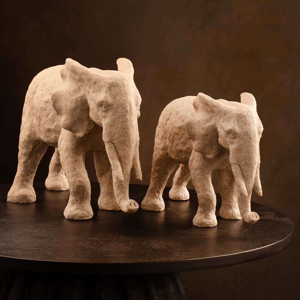 Two  elephant sculptures on a dark surface with a brown background