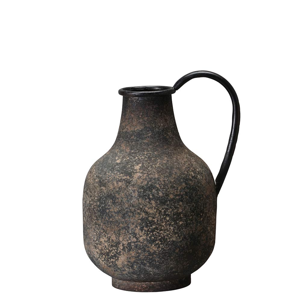 A rustic dark brown and black metal  pitcher with a textured, speckled finish and a curved handle, isolated on a white background.