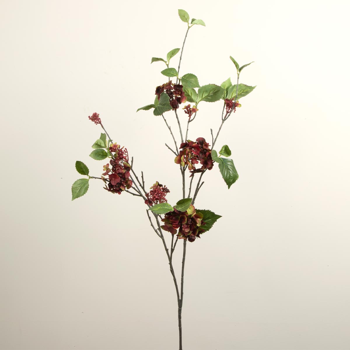 Artificial Hydrangea spray with red and green flowers and leaves on a white background.