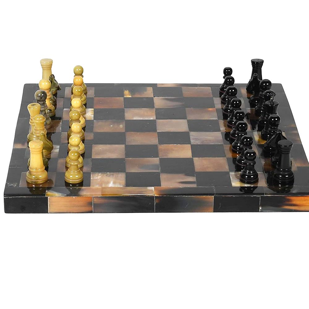 A polished horn chess set with a tortoiseshell-patterned board featuring alternating black, brown, and amber squares, accompanied by black and green-beige chess pieces on a white background.